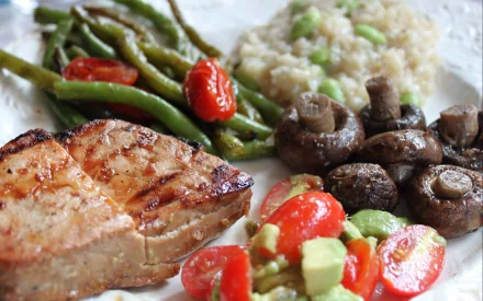 A vibrant meal featuring grilled meat alongside green beans, cherry tomatoes, mushrooms, and a creamy rice dish, captured in a high-definition desktop wallpaper.