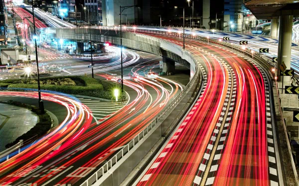 Time-lapse photography captures vibrant light trails from vehicles on a busy multi-level highway at night, creating a dynamic HD PC desktop wallpaper background.