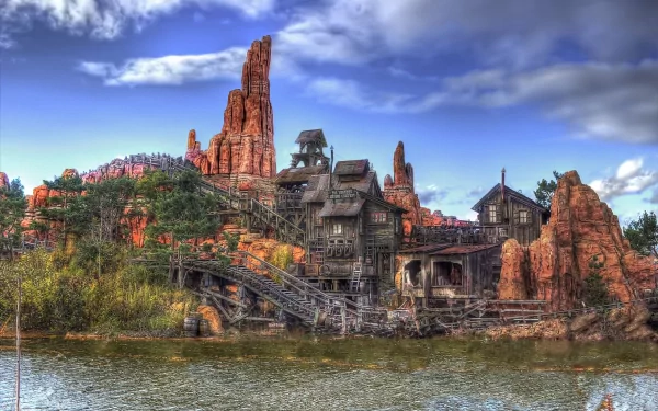 HD PC desktop wallpaper showcasing a man-made ruin nestled among red rock formations under a vibrant blue sky with scattered clouds.
