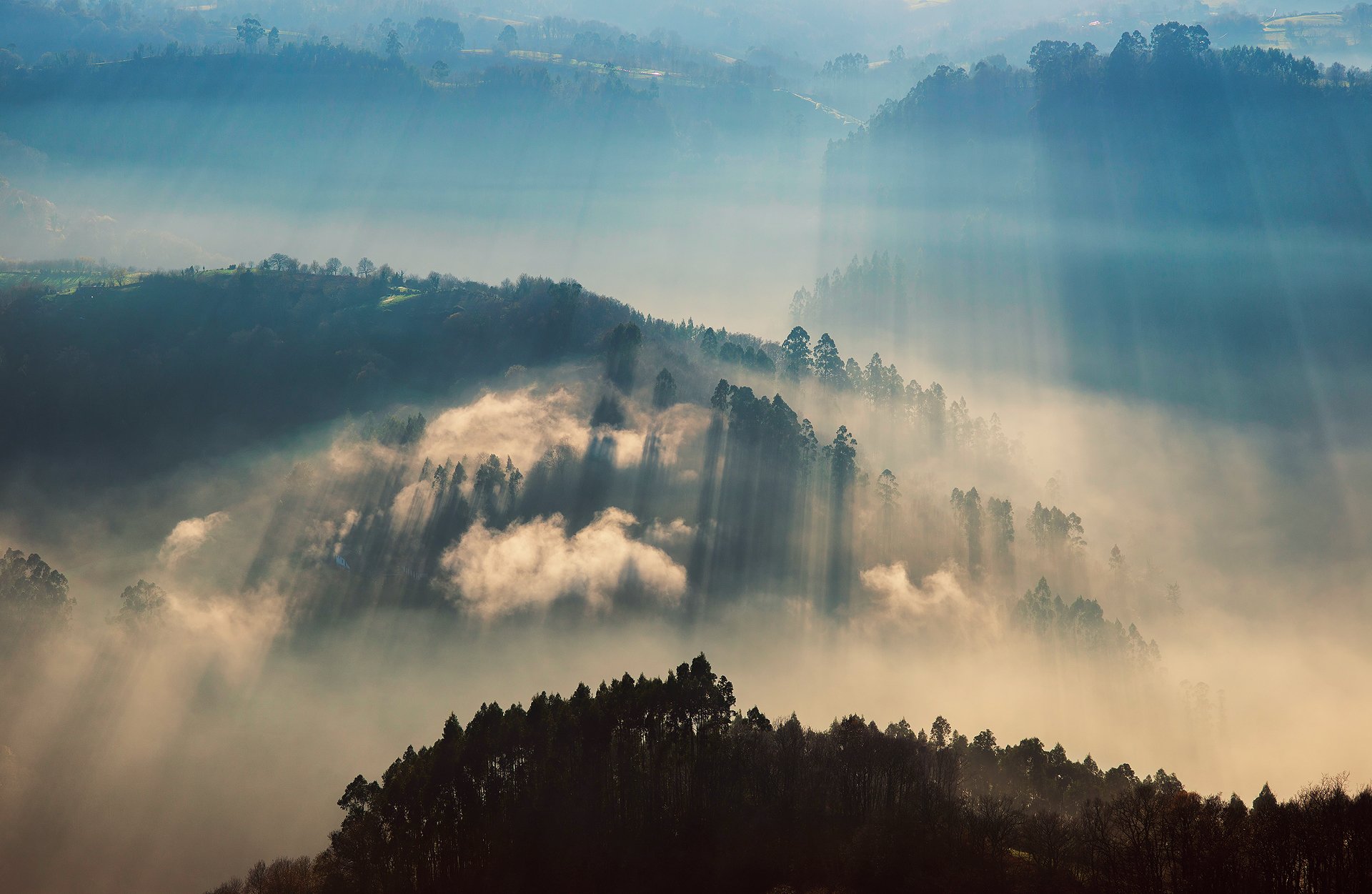 A serene landscape of misty hills illuminated by sunbeams, showcasing the beauty of nature in rich colors, making it an inspiring HD desktop wallpaper.