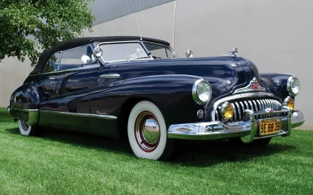 Classic vehicle: navy 1949 Buick Roadmaster Convertible on grass with chrome and whitewall tires — 2K Quad HD PC desktop wallpaper/background.