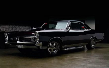 HD desktop wallpaper featuring a sleek black Pontiac GTO muscle car with polished chrome details against a dark background.
