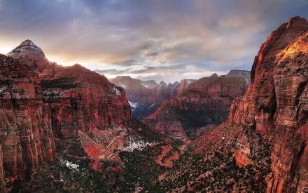 HD desktop wallpaper capturing the dramatic canyon landscape of Zion National Park under a colorful, cloudy sky at sunset.