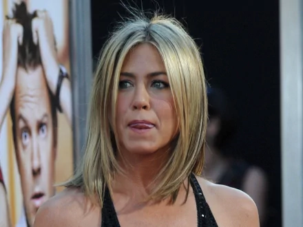 HD desktop wallpaper featuring actress Jennifer Aniston with shoulder-length blonde hair and a thoughtful expression at a public event.