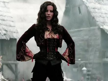 Anna Valerious, portrayed by Kate Beckinsale, stands confidently in a dark, detailed costume against a misty, historic backdrop from the movie Van Helsing.