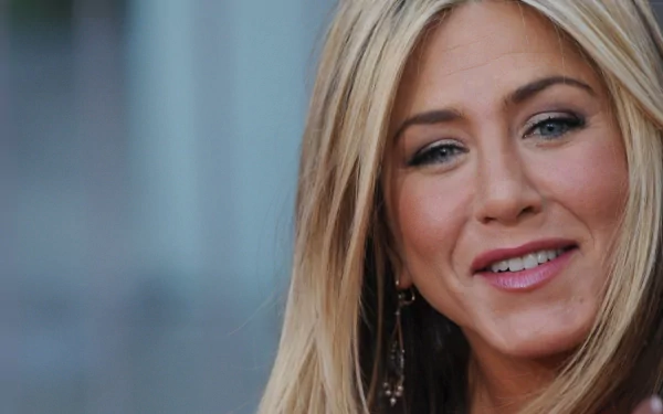 A close-up shot of Jennifer Aniston, showcasing her warm smile and elegant style, designed as a high-definition desktop wallpaper and background.