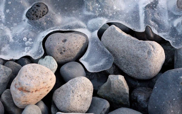 HD nature desktop wallpaper featuring smooth stones partially covered by translucent ice, showcasing intricate textures and natural winter elements.
