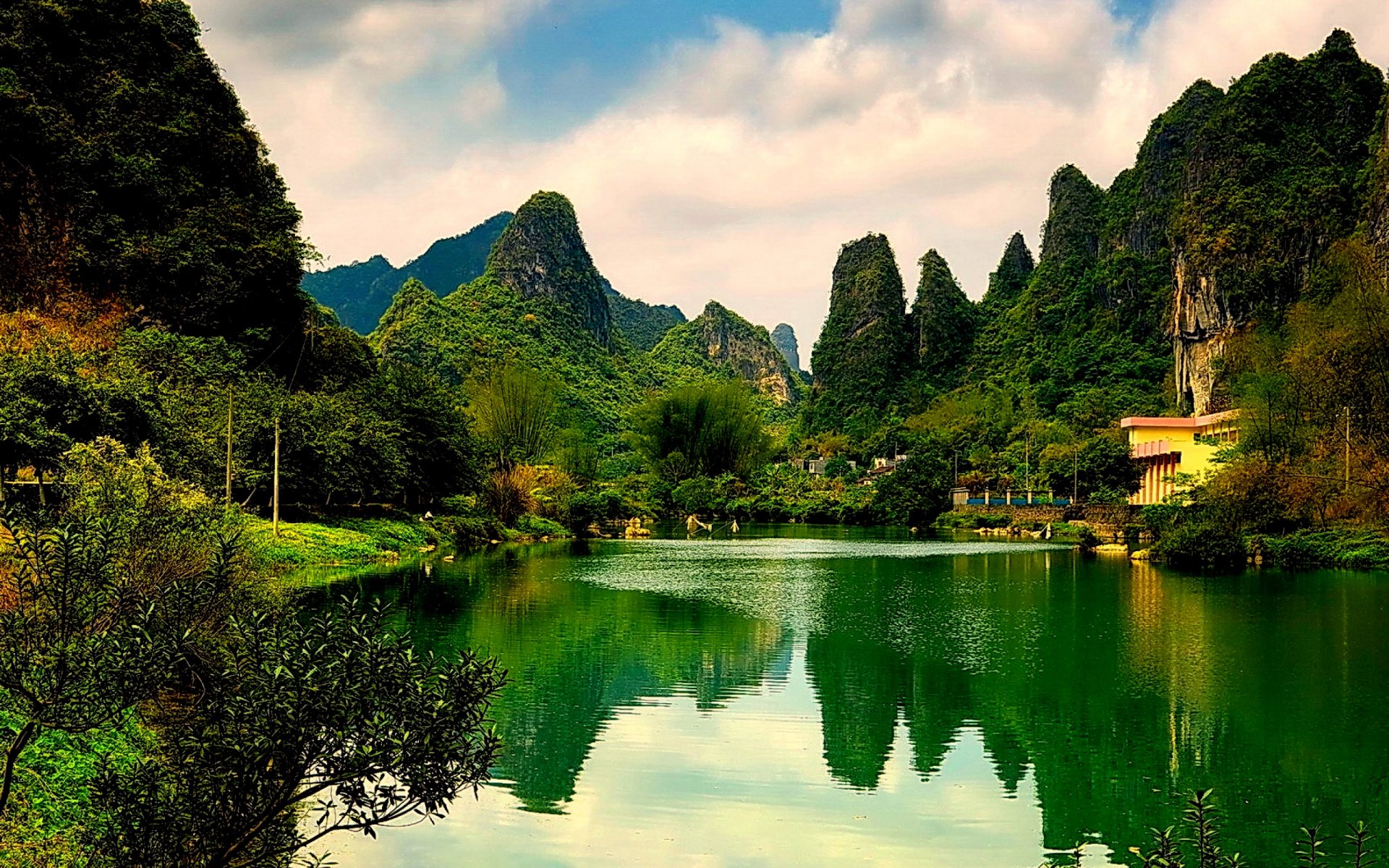 A tranquil scenic photograph showcasing lush green mountains reflected in a serene lake, providing an enchanting backdrop for a HD desktop wallpaper.