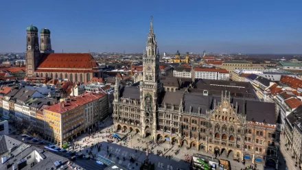 A high-definition desktop wallpaper showcasing the iconic man-made architecture of Munich, featuring its historic central square and prominent buildings under a clear blue sky.