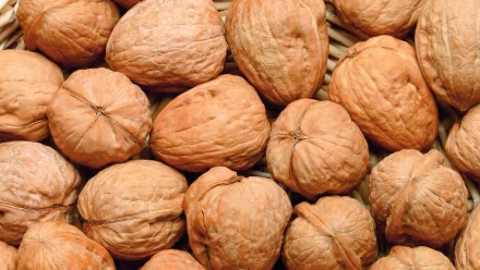HD desktop wallpaper featuring a close-up view of whole walnuts in their shells, highlighting their natural texture and earthy tones.