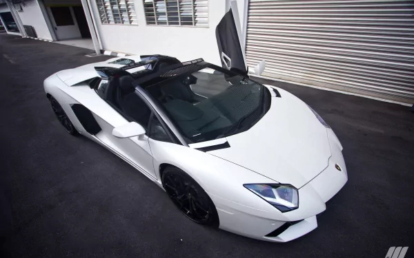 HD desktop wallpaper featuring a white Lamborghini Aventador parked on a street, with one door open, against a backdrop of buildings and a garage door.