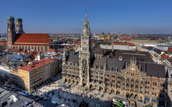 A high-definition desktop wallpaper showcasing the iconic man-made architecture of Munich, featuring its historic central square and prominent buildings under a clear blue sky.
