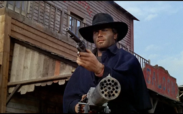 HD PC desktop wallpaper background from the movie Django: a lone cowboy in a wide-brim hat aims a revolver and a Gatling-style gun in front of wooden frontier buildings.