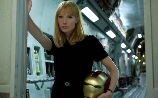 Pepper Potts, portrayed by Gwyneth Paltrow, stands confidently holding Iron Man's helmet in a scene from **Iron Man 2**. The image serves as an engaging HD wallpaper for fans of the movie.