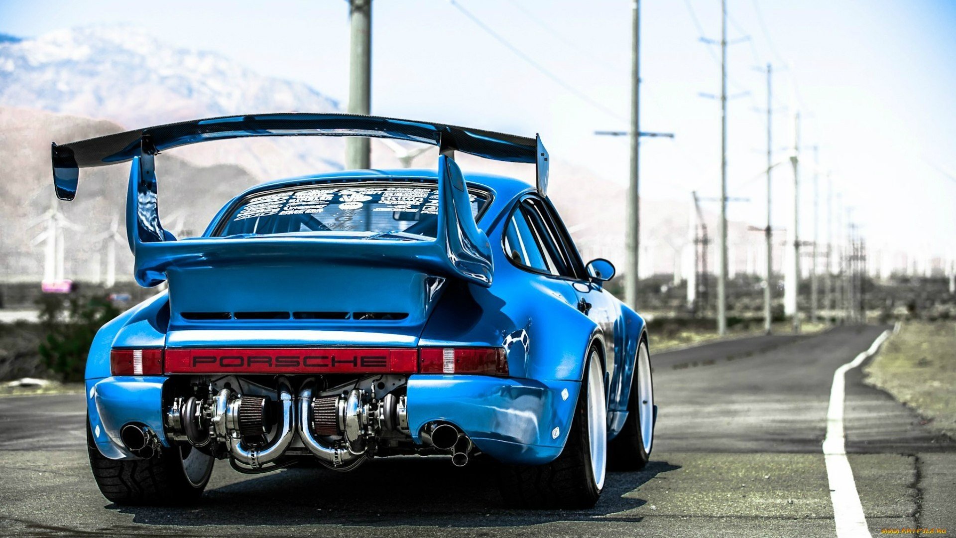 HD desktop wallpaper featuring the rear view of a blue Porsche on a road with power lines in the background.