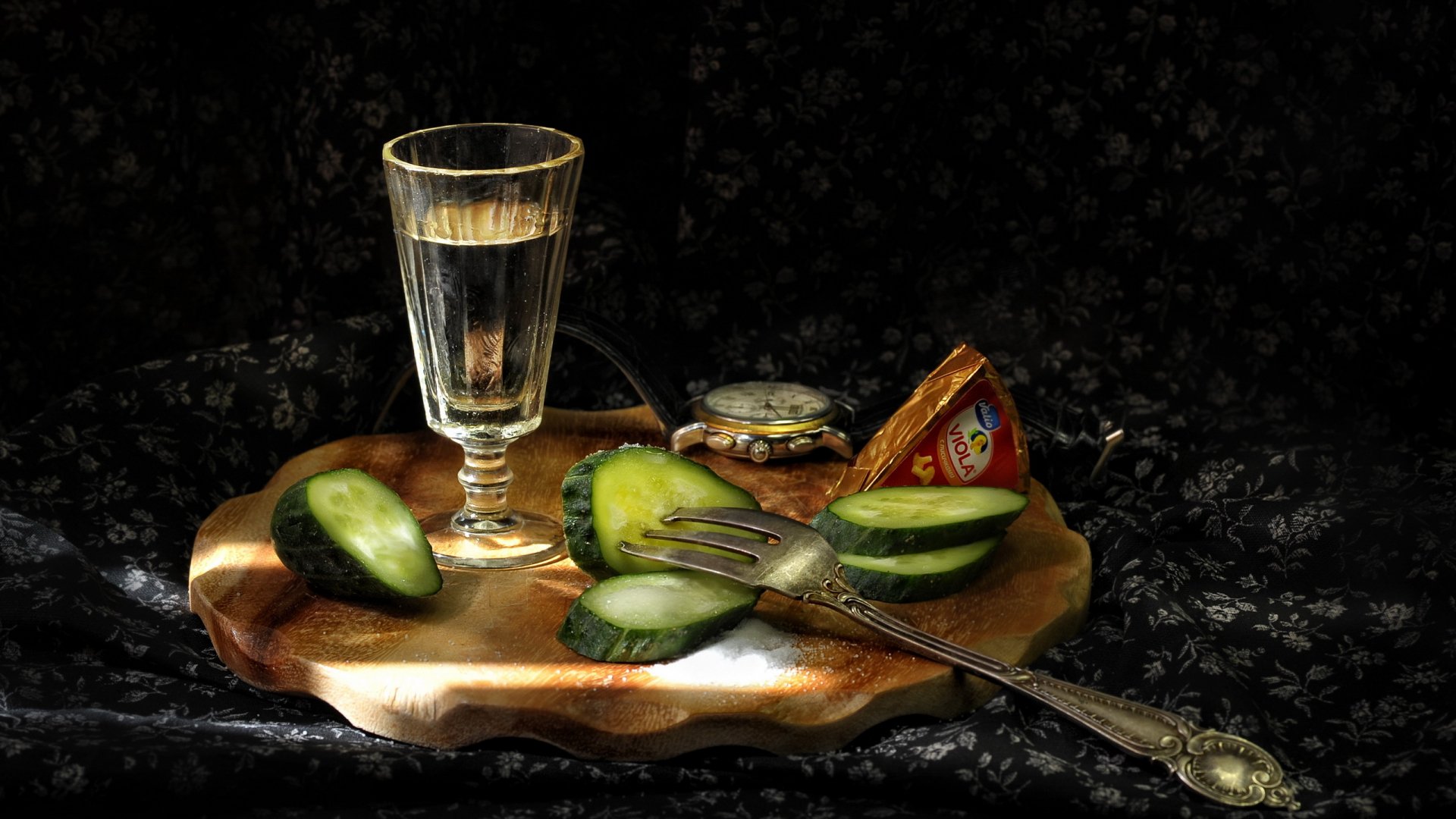 HD desktop wallpaper featuring sliced cucumbers, a glass of clear wine, and a vintage fork arranged on a decorative wooden tray against a dark, textured background.