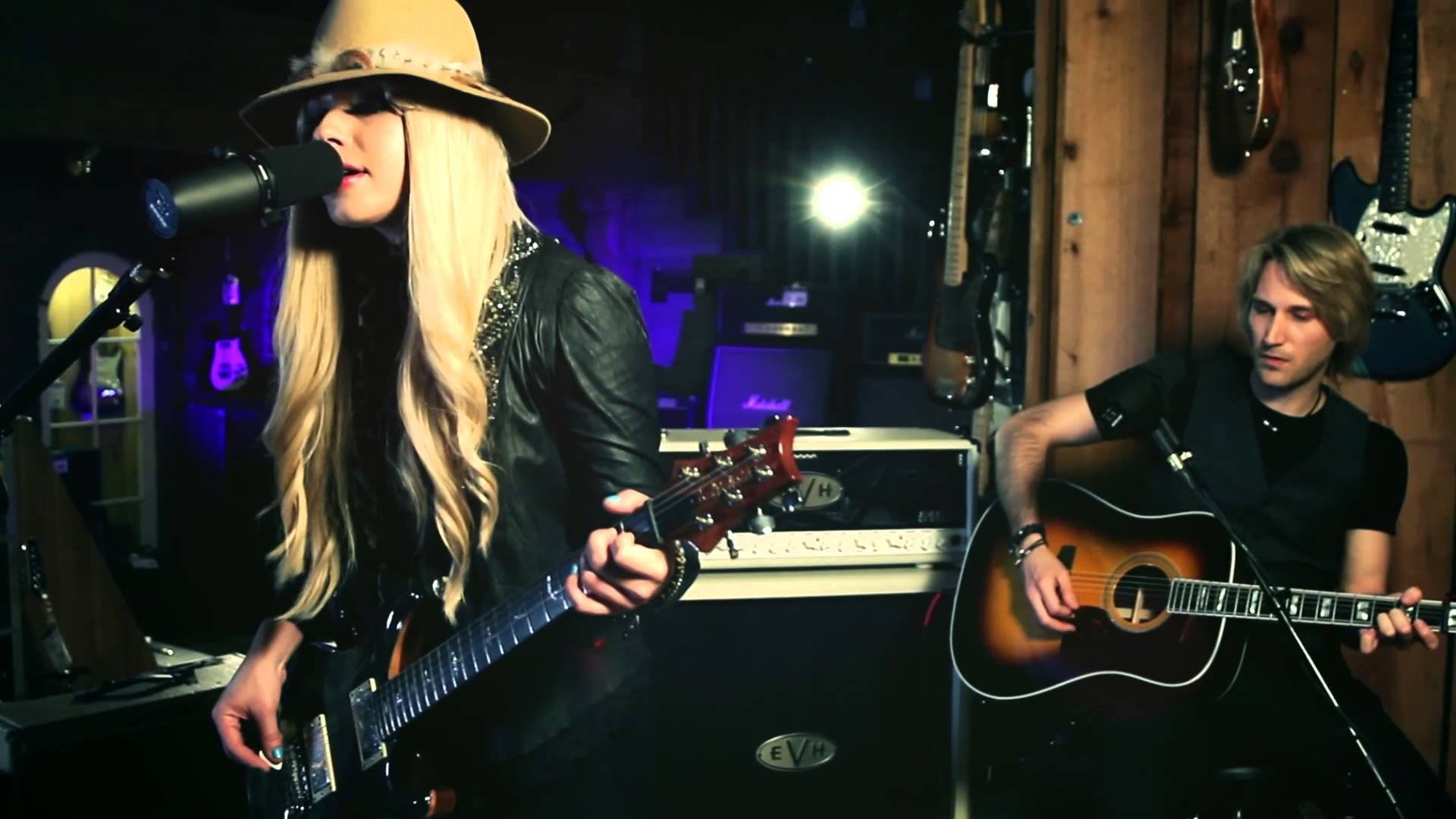 HD PC desktop wallpaper featuring Orianthi performing music with electric and acoustic guitars in a dimly lit studio setting.