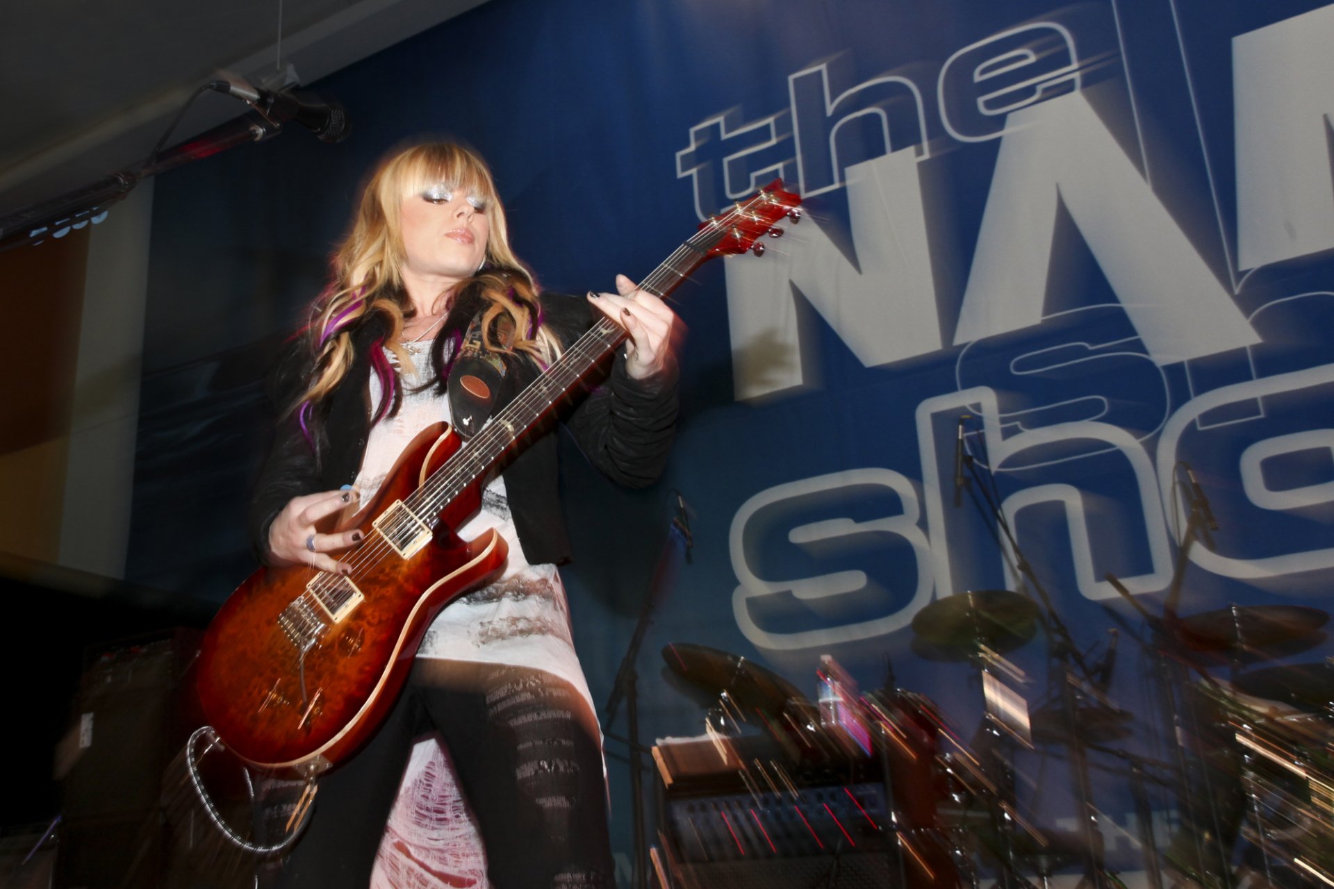 HD desktop wallpaper featuring Orianthi playing an electric guitar on stage during a live music performance.