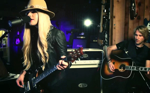HD PC desktop wallpaper featuring Orianthi performing music with electric and acoustic guitars in a dimly lit studio setting.