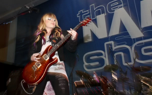 HD desktop wallpaper featuring Orianthi playing an electric guitar on stage during a live music performance.