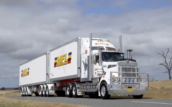 HD PC desktop wallpaper featuring a white Kenworth truck hauling dual trailers on a rural road under a cloudy sky.