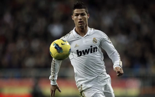 HD wallpaper of Cristiano Ronaldo in action, wearing a Real Madrid C.F. jersey, focusing on a soccer ball during a match.