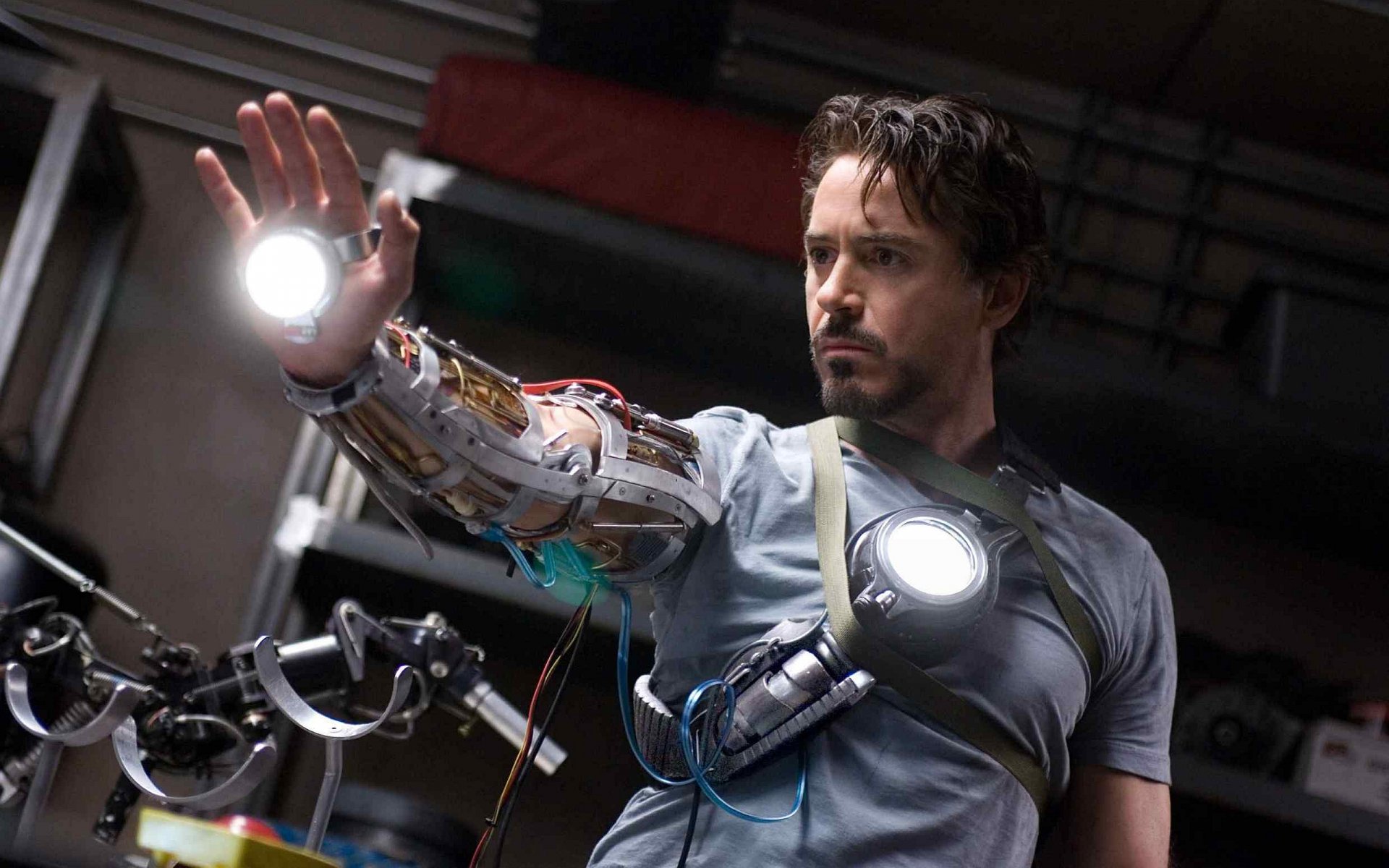 Robert Downey Jr. as Iron Man, showcasing a futuristic arm suit with glowing elements in a dramatic pose, provides a striking HD desktop wallpaper and background.