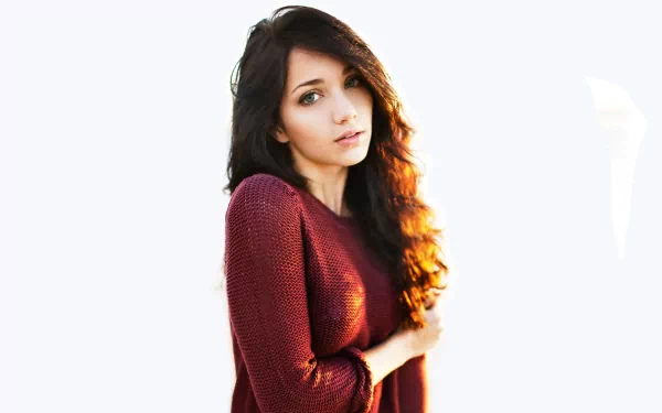 A high-definition wallpaper featuring American model Emily Rudd. She poses with long, flowing hair and wearing a burgundy sweater against a white background.