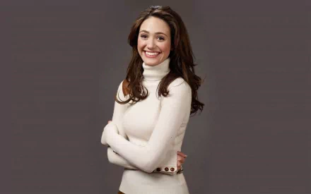 HD desktop wallpaper featuring celebrity Emmy Rossum smiling with arms crossed, wearing a white turtleneck against a plain gray background.