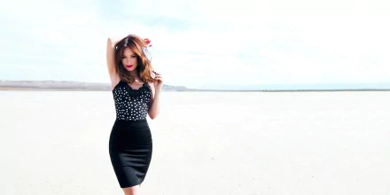 Olivia Wilde poses confidently in a stylish black and white outfit against a bright, expansive backdrop, creating a striking HD desktop wallpaper.