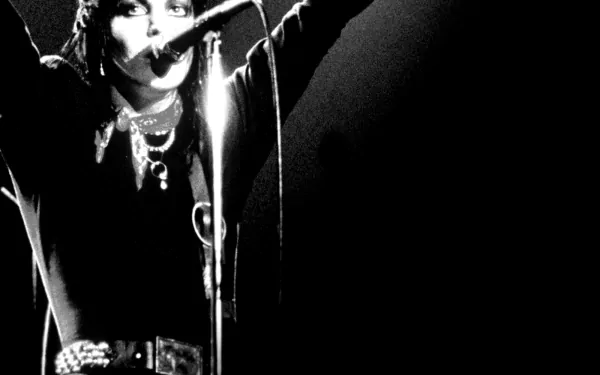 High-definition desktop wallpaper featuring Joan Jett performing, captured in a dynamic moment with arms raised, embodying the essence of music and rock energy.
