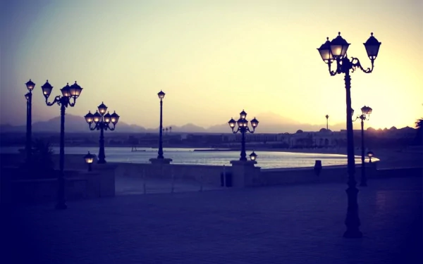 HD PC desktop wallpaper featuring a serene waterfront view with man-made vintage lamp posts glowing softly at dusk.