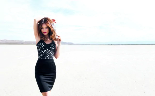 Olivia Wilde poses confidently in a stylish black and white outfit against a bright, expansive backdrop, creating a striking HD desktop wallpaper.