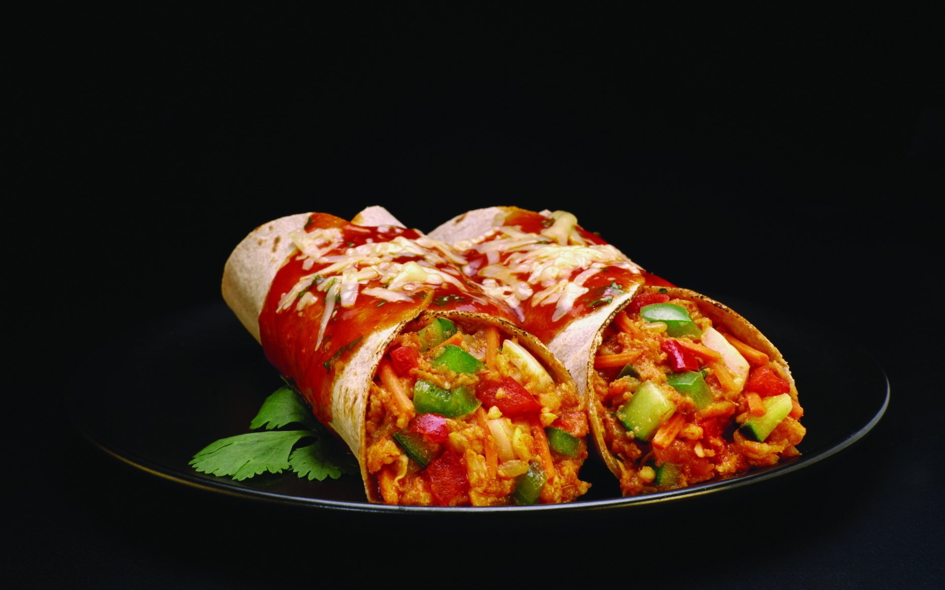 HD PC desktop wallpaper of two vibrant, freshly made burritos filled with chicken, beans, tomatoes, and topped with melted cheese on a black plate against a dark background.