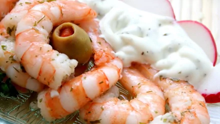 A delicious serving of shrimp arranged with a creamy dip and garnished with an olive, making for an appetizing meal. This HD wallpaper captures the essence of gourmet food.
