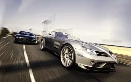 Silver Mercedes-Benz SL-Class and black Audi R8 supercars speeding side by side on a blurred road, captured in an HD desktop wallpaper background.