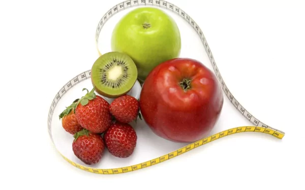 A vibrant assortment of fruits, including red and green apples, strawberries, and kiwi, arranged with a measuring tape, creates a fresh food-themed HD desktop wallpaper.