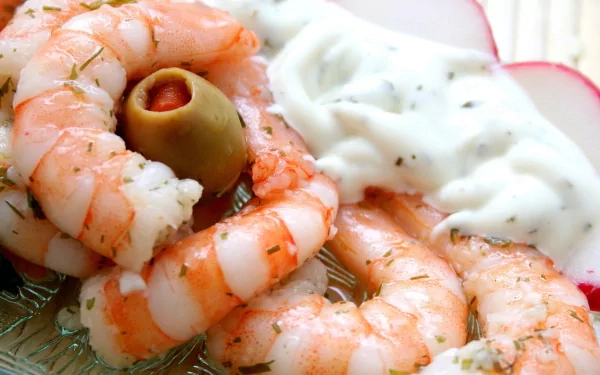 A delicious serving of shrimp arranged with a creamy dip and garnished with an olive, making for an appetizing meal. This HD wallpaper captures the essence of gourmet food.