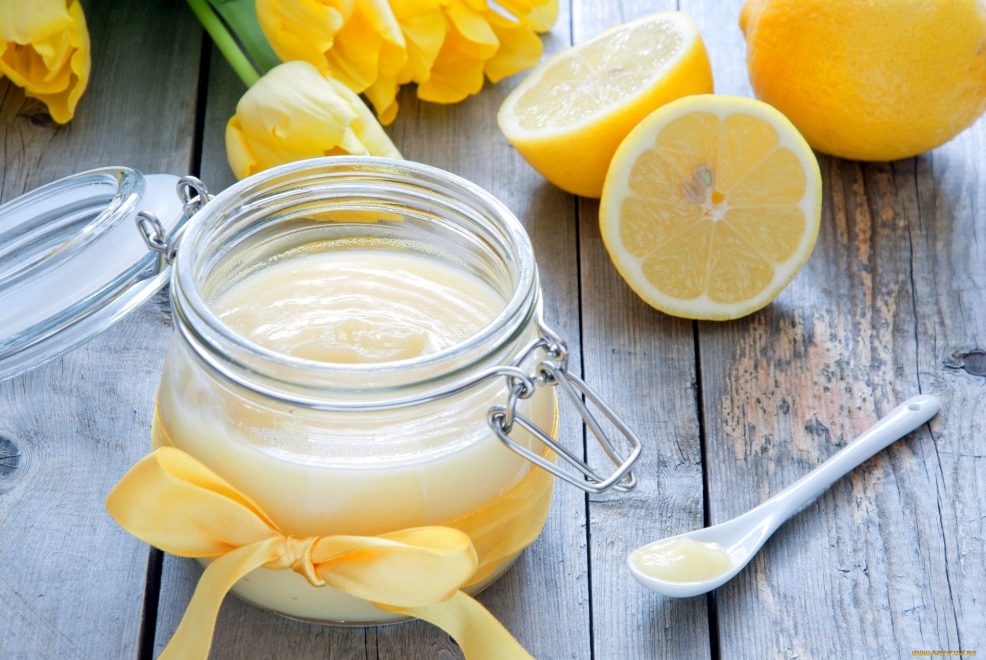 HD PC wallpaper featuring a jar of creamy lemon dessert with fresh lemon halves and yellow flowers on a rustic wooden table, highlighting food and sweets.