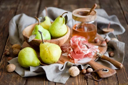 A still life composition featuring fresh pears, cured ham, and honey on a rustic wooden surface, complementing a warm and inviting atmosphere for HD desktop wallpaper.
