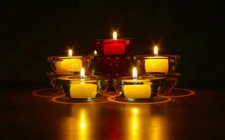 HD photography of six lit candles arranged in a pyramid, casting warm reflections on a dark surface, designed as a PC desktop wallpaper and background.
