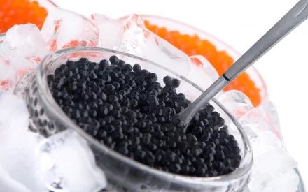 HD desktop wallpaper featuring black caviar in a glass bowl on ice with a spoon, surrounded by orange caviar, highlighting luxurious food presentation.