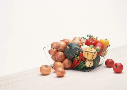 HD desktop wallpaper featuring a wire basket filled with onions, tomatoes, peppers, and squash against a clean white background.