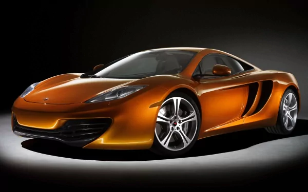 A striking orange McLaren MP4-12C supercar, showcased in a dramatic light setting, epitomizing luxury and performance in this stunning 4K Ultra HD desktop wallpaper.