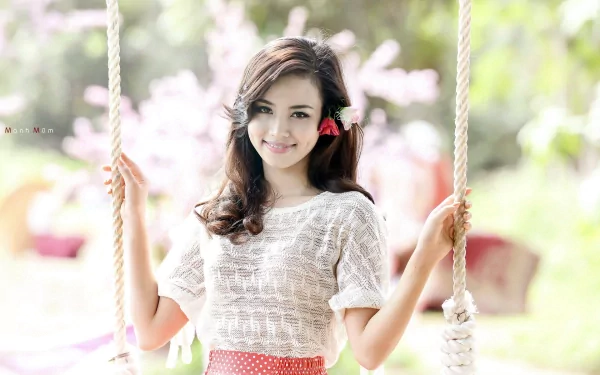 HD desktop wallpaper of a woman with a cheerful mood, smiling while sitting on a swing in a bright, outdoor setting.