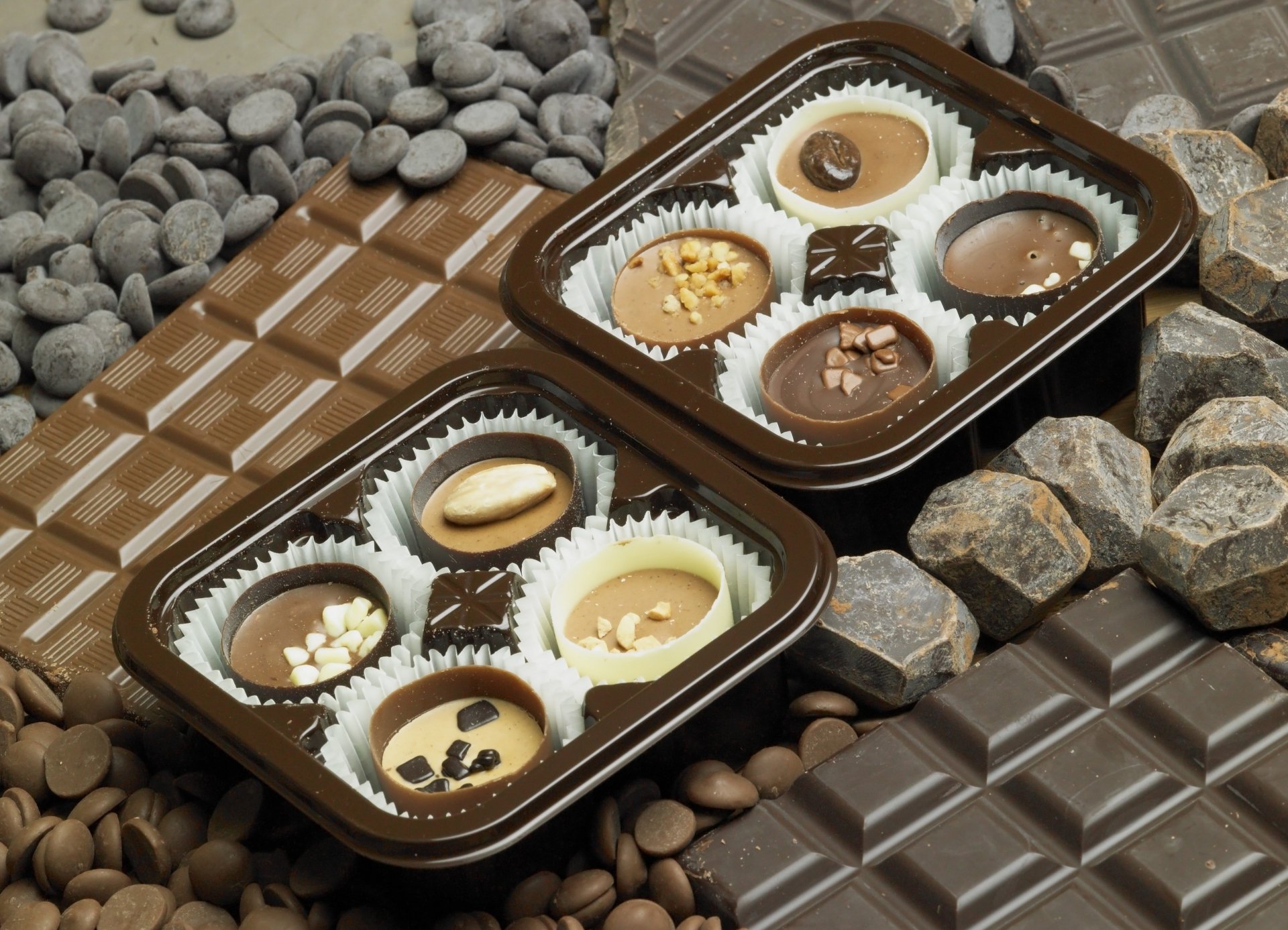 A rich array of chocolates displayed in a box, surrounded by various chocolate textures and ingredients, captured in a stunning 4K Ultra HD desktop wallpaper.