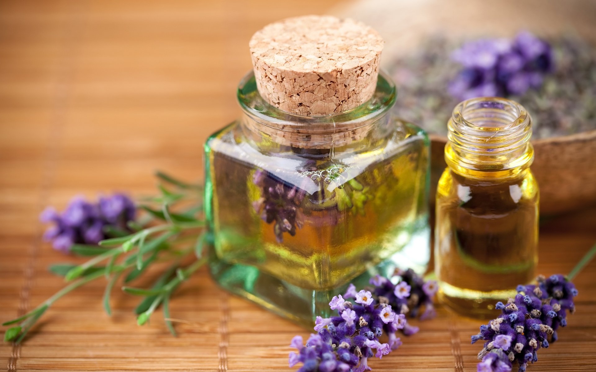 HD desktop wallpaper featuring a man-made spa setting with essential oils, lavender sprigs, and a corked glass bottle on a wooden surface.