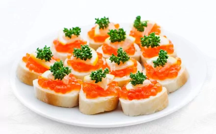 HD PC desktop wallpaper featuring close-up of appetizing caviar-topped bread bites garnished with fresh herbs on a white plate.