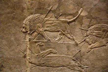 HD PC desktop wallpaper featuring an artistic Assyrian lion hunt relief carved in ancient stone, showcasing dynamic lions and hunters in motion.