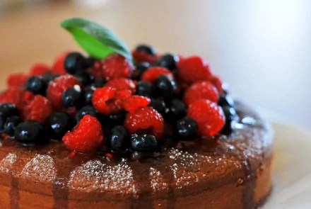 Close-up of a chocolate cake topped with fresh raspberries and blueberries, captured in 4K Ultra HD for a vibrant PC desktop wallpaper background.